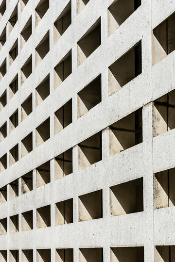 Concrete wall with square openings creating a pattern of shadows.